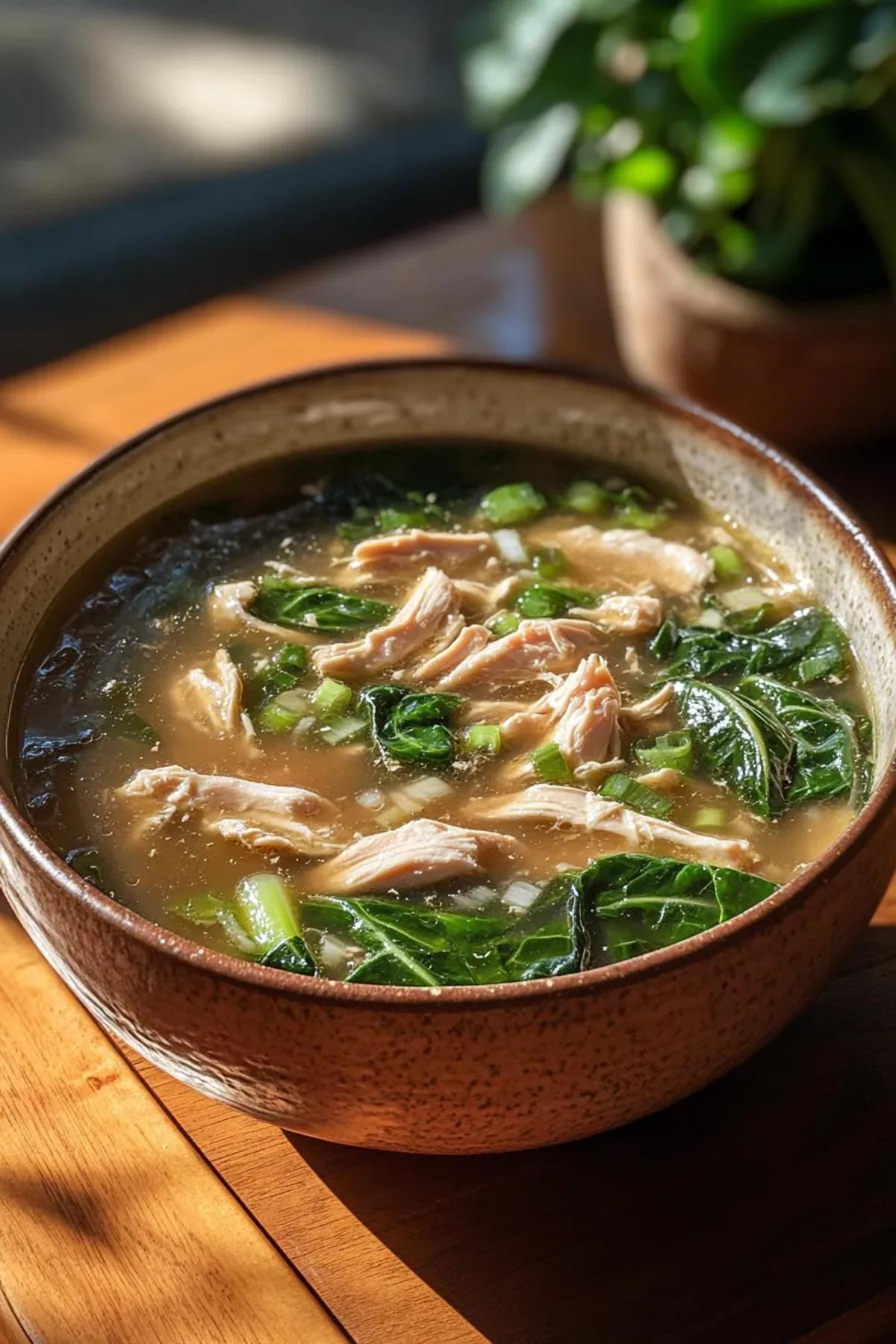 A steaming bowl of slow cooker chicken and bok choy soup, showcasing tender shredded chicken, bright green bok choy leaves, and a golden broth garnished with sliced scallions and sesame seeds on a rustic wooden table card